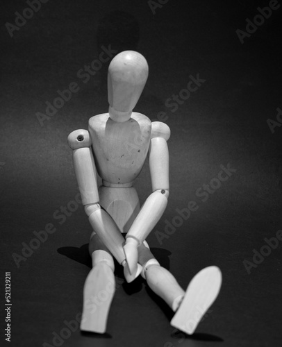 sad wooden mannequin on a black background