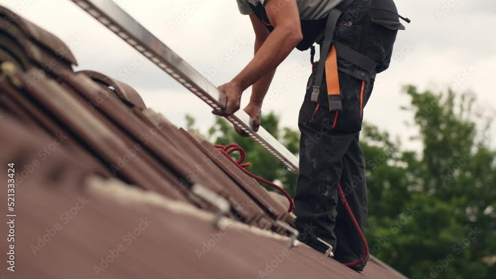 Ground level view of roofer worker adding mounts for solar panel home, day Ground level view of roofer worker adding mounts for solar panel home, day