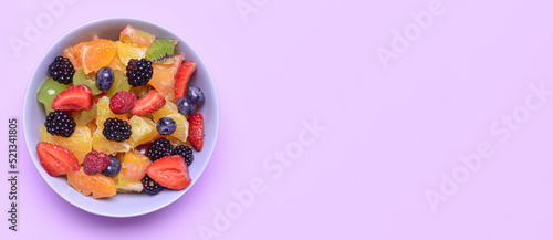 Plate of tasty fruit salad on lilac background with space for text
