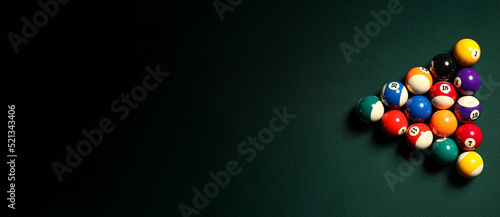 Pyramid made of billiard balls on dark background with space for text photo