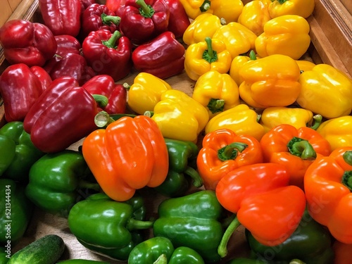 Fotografia A closeup photo of green, yellow, orange and red bell peppers at a market