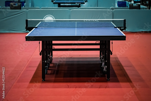 фотографія Blue table tennis or pingpong table is settle on a red, orange floor of the indoor court stadium for competitions tournament