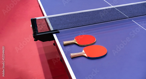 Two pingpong table tennis rackets for playing are laid on next to net on the blue table. This is one of ping pong sports equipment for players...