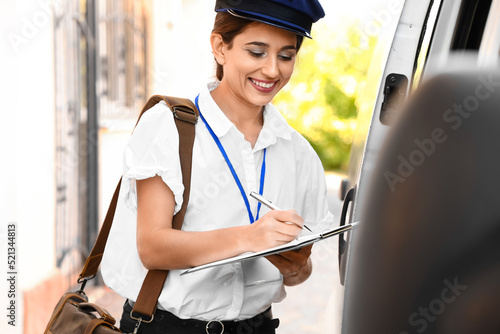 Young postwoman writing in ...
