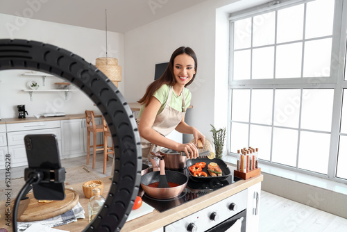 Young woman frying fish wit...