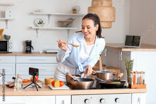 Young woman recording cooking video tutorial in kitchen