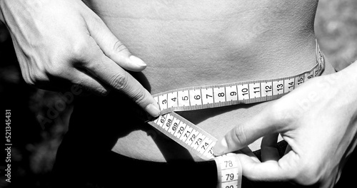 girl measuring her waist with black and white toned photo