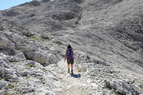 young woman walking during a high mountain hike on the Italian Dolomite on the stony path