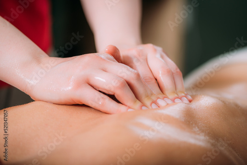 Massaging with massage oil  hands of a female massage therapist massaging a female client