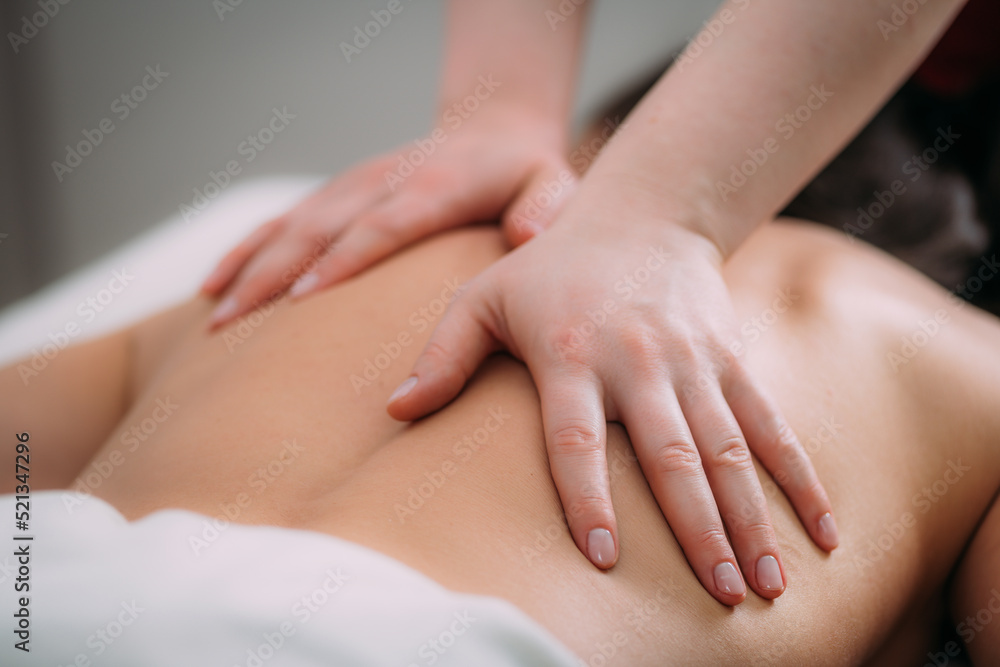 Back massage in a massage salon, woman having a relaxing back massage. Back massage in a massage salon, woman having a relaxing back massage.