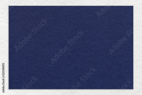 Texture of craft navy blue color paper background with white border, macro. Vintage dense kraft denim cardboard © nikol85