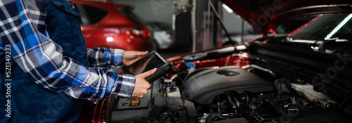 Caucasian female auto mechanic uses a special computer to diagnose faults. 