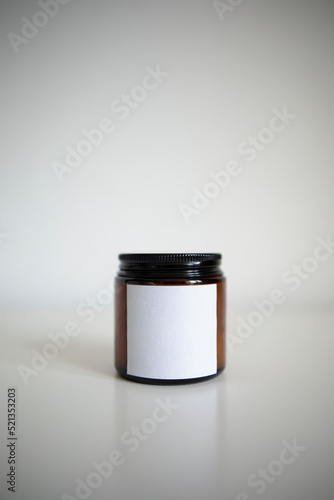 dark glass jar with a white empty label on a white background. closed jar with a candle or cream close-up.