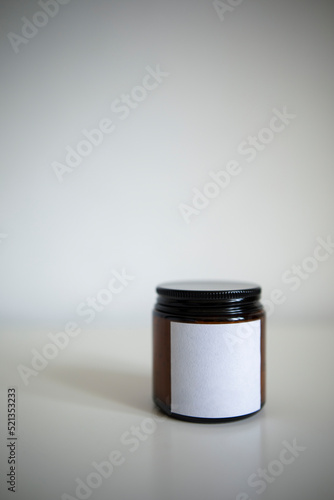 dark glass jar with a white empty label on a white background. closed jar with a candle or cream close-up. 