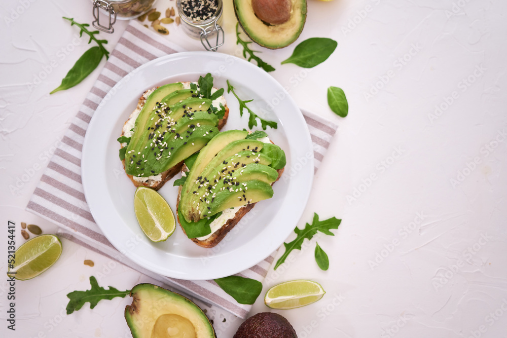 Freshly made Avocado and cream cheese toasts on a white ceramic plate and ingredients Freshly made Avocado and cream cheese toasts on a white ceramic plate and ingredients