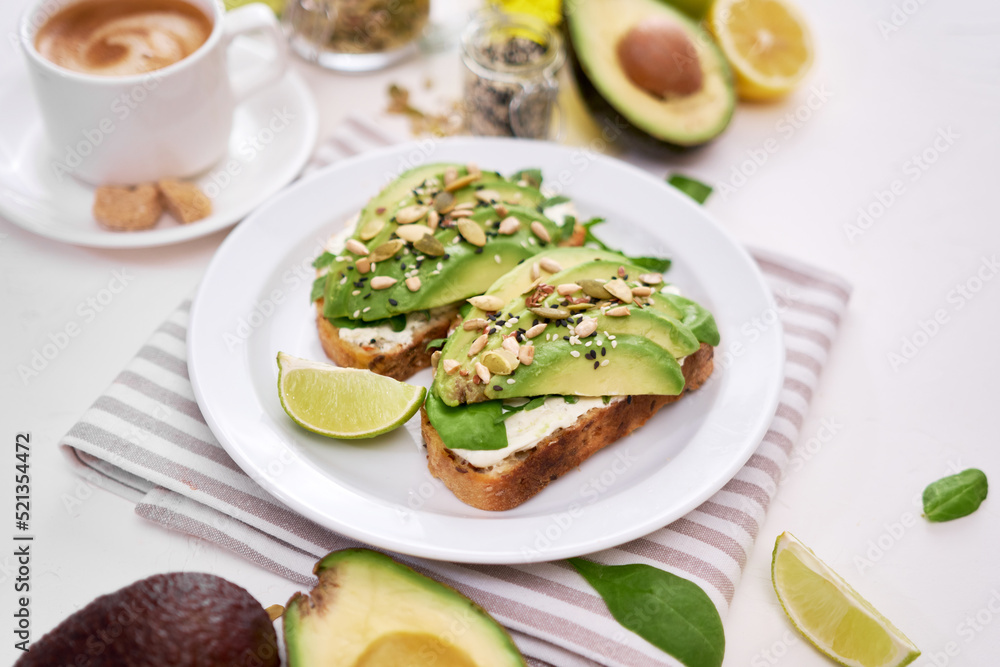 Freshly made Avocado and cream cheese toasts on a white ceramic plate and ingredients