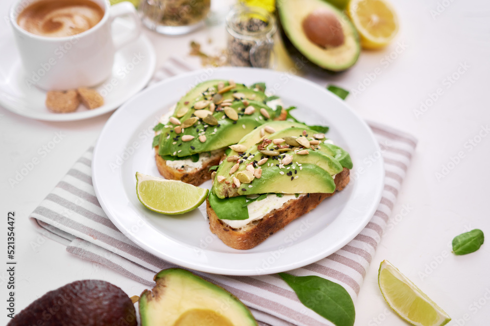 Freshly made Avocado and cream cheese toasts on a white ceramic plate and ingredients Freshly made Avocado and cream cheese toasts on a white ceramic plate and ingredients
