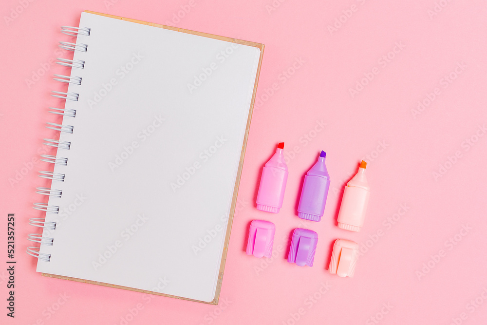 Back to school. Opened copybook and markers on pink background. Flat lay. Mock up. Concept of education Back to school. Opened copybook and markers on pink background. Flat lay. Mock up. Concept of education