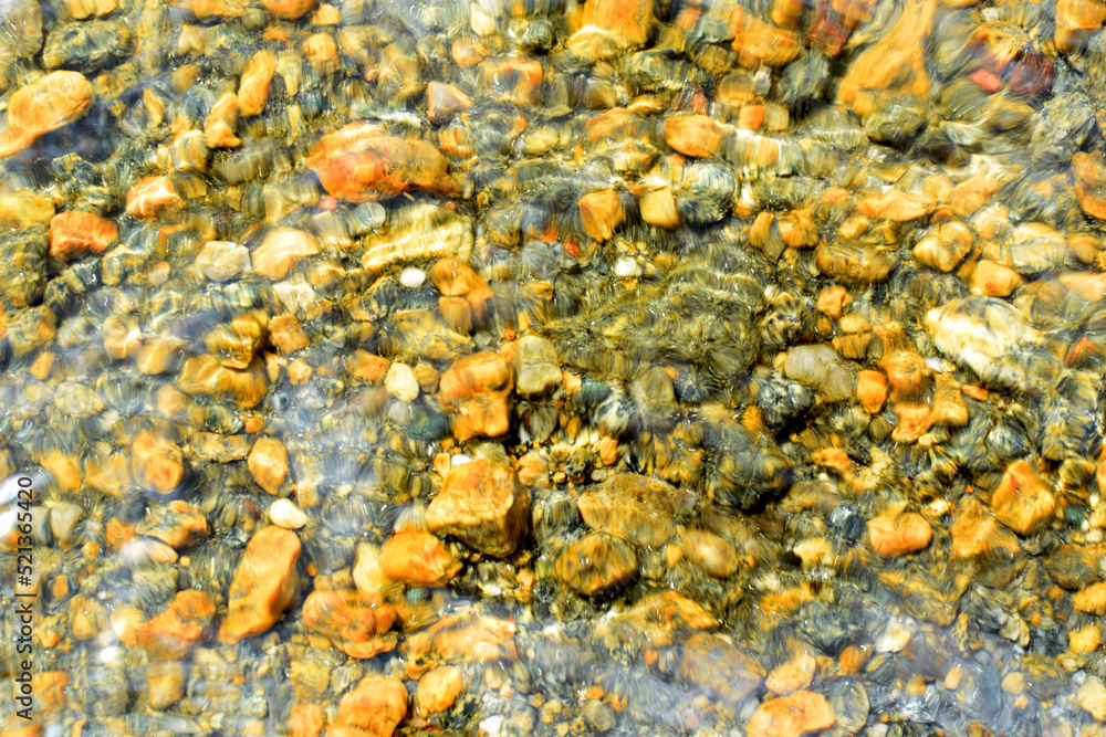 Bright yellow sea stones at the bottom of the sea, sun glare on the surface. Blurred background, selective focus. Summer holiday concept.