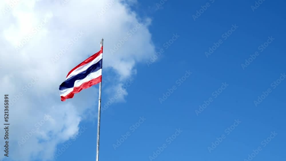 Photograph the Thai flag with three colors red white and blue in a slow motion on a tall pole against the sky. a little cloudy The wind blows the flag fluttering in the wind. Photograph the Thai flag with three colors red white and blue in a slow motion on a tall pole against the sky. a little cloudy The wind blows the flag fluttering in the wind.