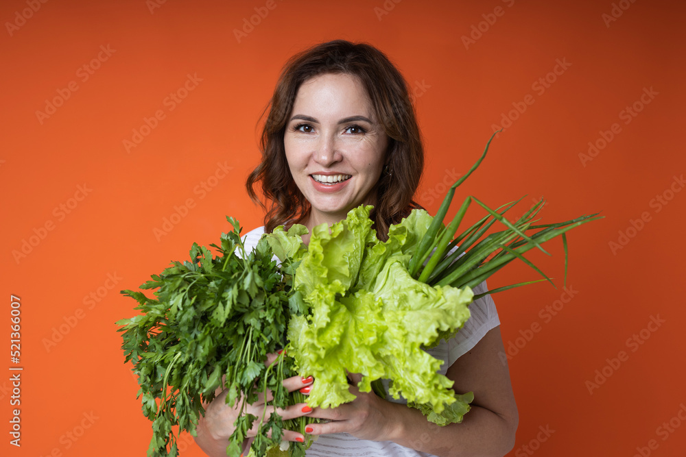 woman in an apron with lettuce and green onions in her hands woman in an apron with lettuce and green onions in her hands