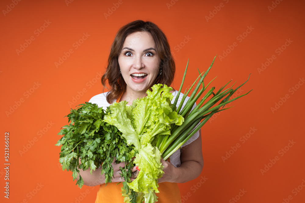 woman in an apron with lettuce and green onions in her hands woman in an apron with lettuce and green onions in her hands