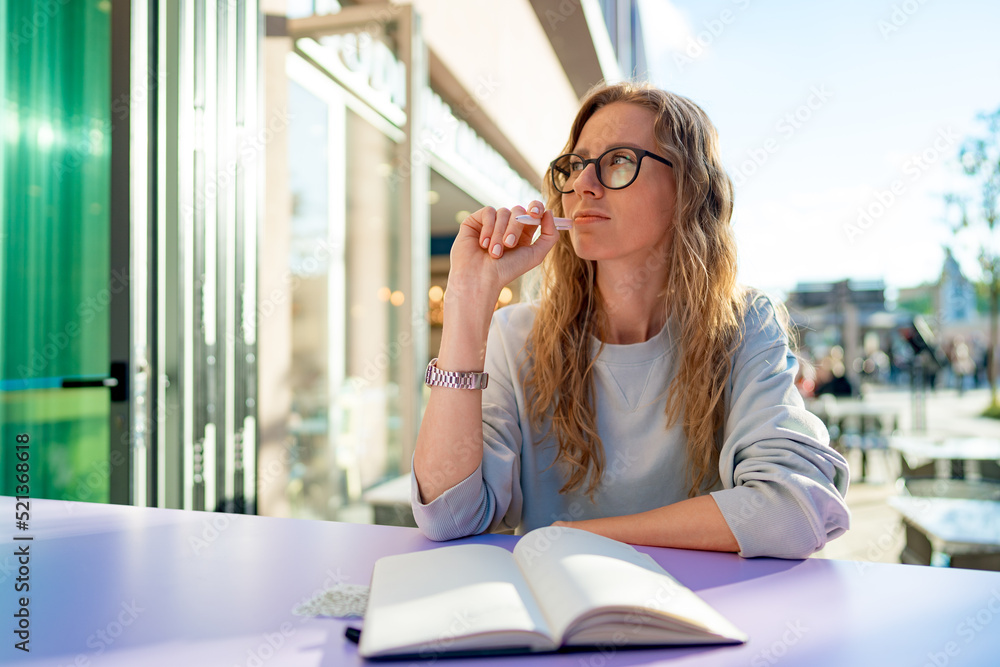 Casual woman sitting at table and taking notes in notebook .on the cafe terrace Casual woman sitting at table and taking notes in notebook .on the cafe terrace