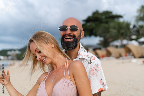 Young multiracial stylish modern couple man and woman on the beach smiling cheerfully, laughing, love, care and affection, romantic