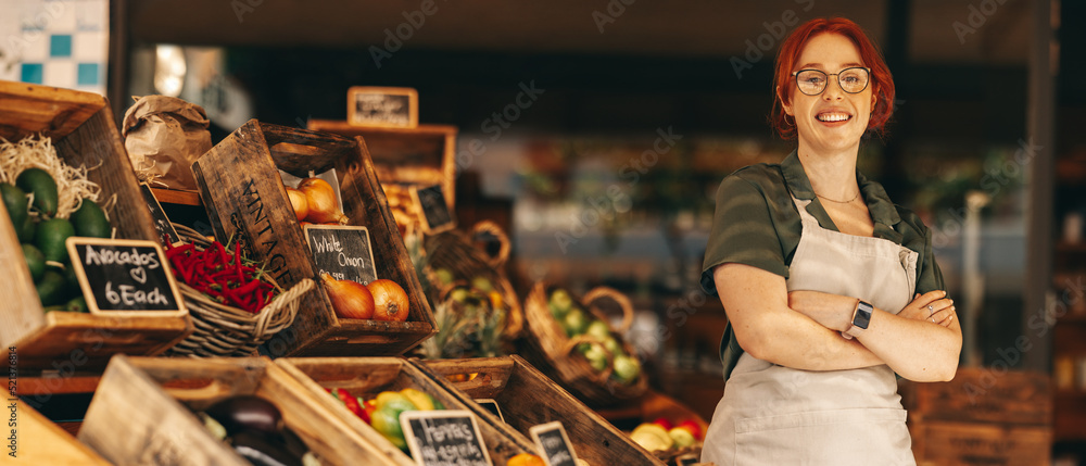 Fototapeta premium Happy supermarket owner smiling at the camera in her shop