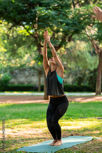 beautiful yoga teacher doing Utkatasana posture in the park © Miguel Valls