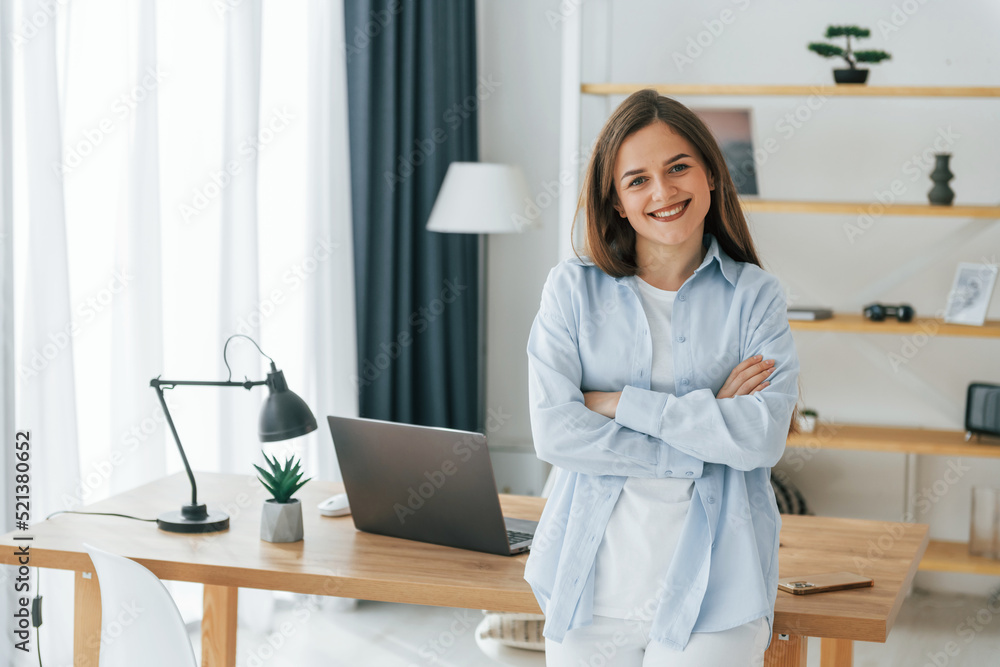 Standing with arms crossed. Young beautiful woman is home alone in domestic room Standing with arms crossed. Young beautiful woman is home alone in domestic room