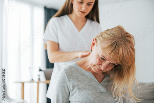 Massaging upper body parts. Senior woman is visiting physician in the office