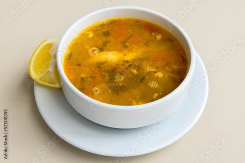 Homemade turkish soup Tavuk Suyu corbasi in a white ceramic soup plate.Turkish noodle chicken broth soup on a plate. Turkish meal (sehriyeli tavuk suyu corbasi)