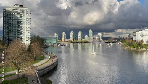 Beautiful view of False Creek's river and boats with the city's buildings under cloudy sky photo