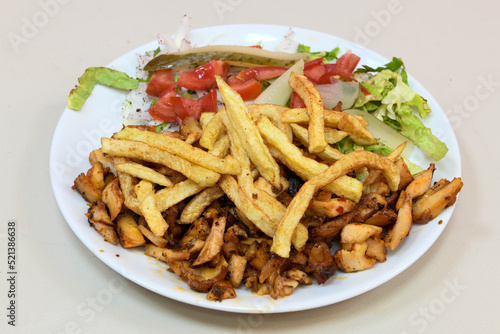 Turkish and Arabic Traditional Ramadan chicken doner kebab with tasty tomato sauce and rice or turkish pilav in white plate on wood table background. (Pilav ustu tavuk doner)