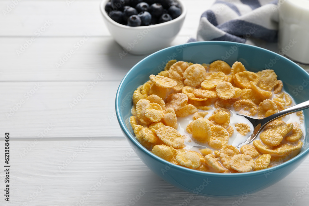 Bowl of tasty corn flakes served on white wooden table. Space for text Bowl of tasty corn flakes served on white wooden table. Space for text