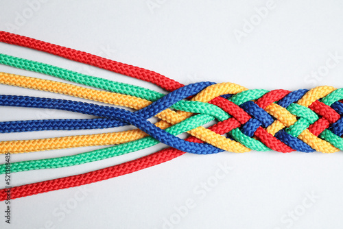 Braided colorful ropes isolated on white, top view. Unity concept