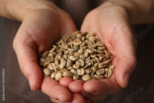 Woman holding pile of green coffee beans, closeup