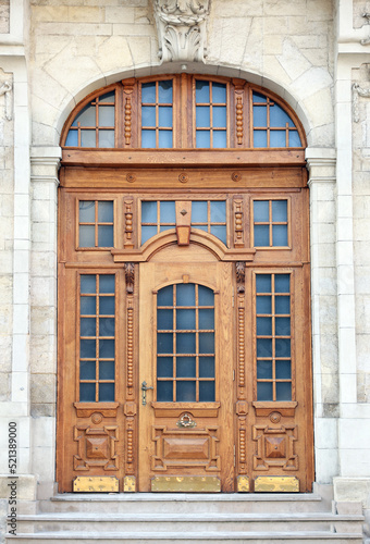 Entrance of house with beautiful arched wooden door, elegant molding and transom window