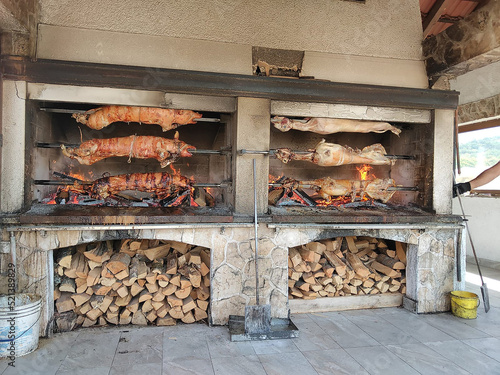View of a large charcoal grill with suckling pig and burning logs photo