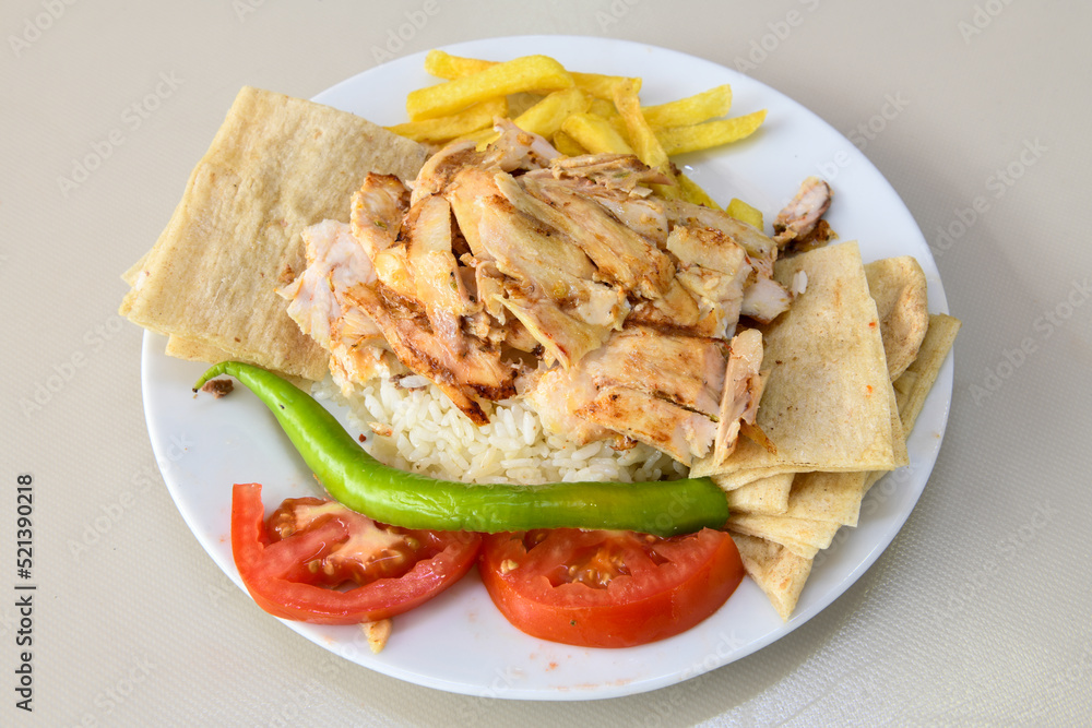 Turkish and Arabic Traditional Ramadan chicken doner kebab with tasty tomato sauce and rice or turkish pilav in white plate on wood table background. (Pilav ustu tavuk doner) Turkish and Arabic Traditional Ramadan chicken doner kebab with tasty tomato sauce and rice or turkish pilav in white plate on wood table background. (Pilav ustu tavuk doner)
