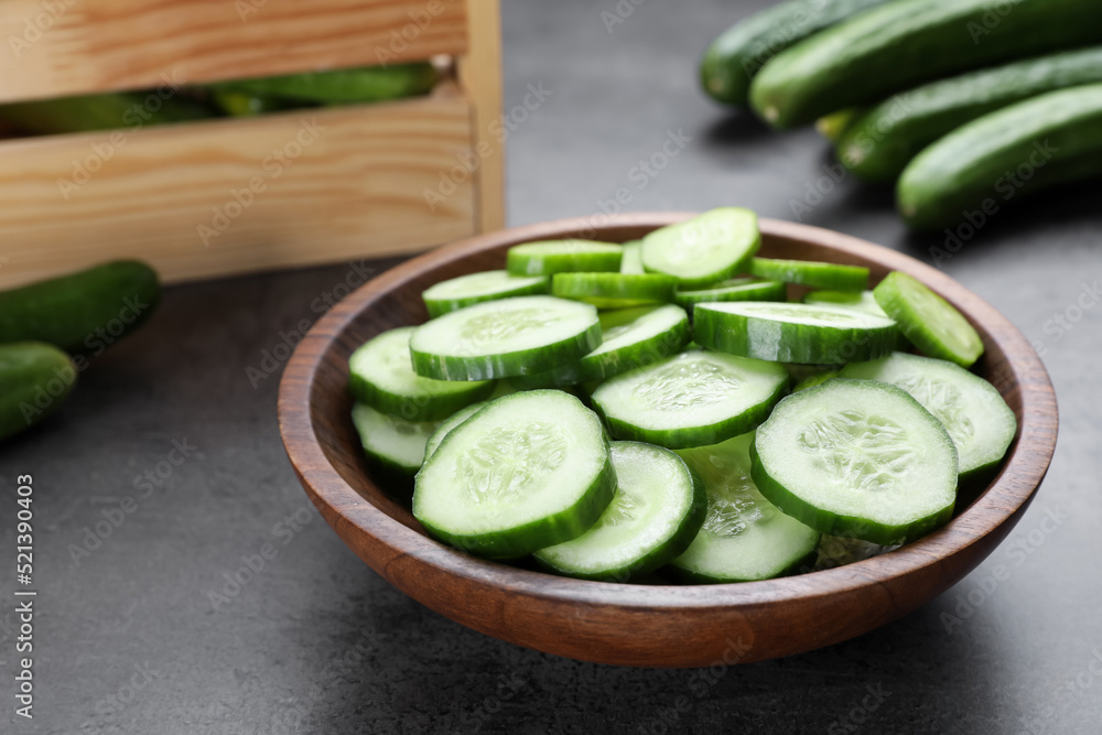 Slices of fresh ripe cucumber in bowl on grey table, closeup Slices of fresh ripe cucumber in bowl on grey table, closeup