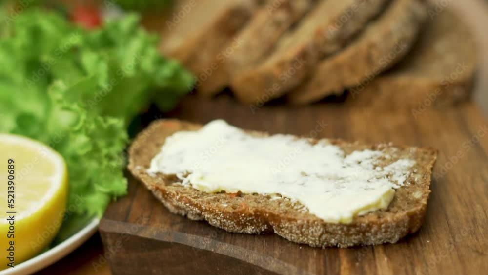Spreading Butter on Fresh Rye Bread for Making a Breakfast Breakfast Sandwich, Close-up. Healthy Food. Spreading Butter on Fresh Rye Bread for Making a Breakfast Breakfast Sandwich, Close-up. Healthy Food.