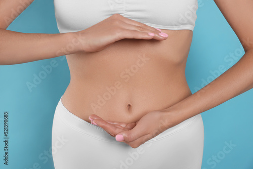 Wallpaper Mural Woman in underwear holding something near her belly on light blue background, closeup. Healthy stomach Torontodigital.ca