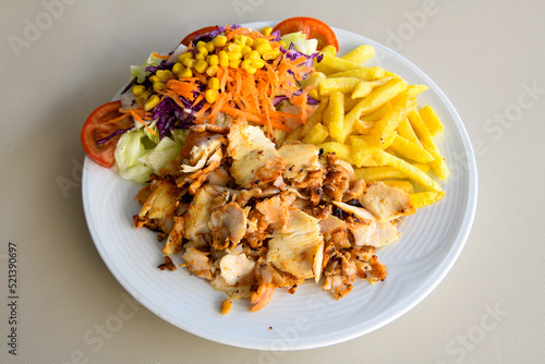 Turkish and Arabic Traditional Ramadan chicken doner kebab with tasty tomato sauce and rice or turkish pilav in white plate on wood table background. (Pilav ustu tavuk doner) photo