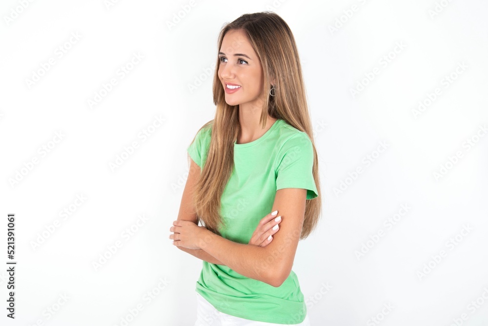 young beautiful woman wearing green T-shirt over white background cross hands look copy space young beautiful woman wearing green T-shirt over white background cross hands look copy space