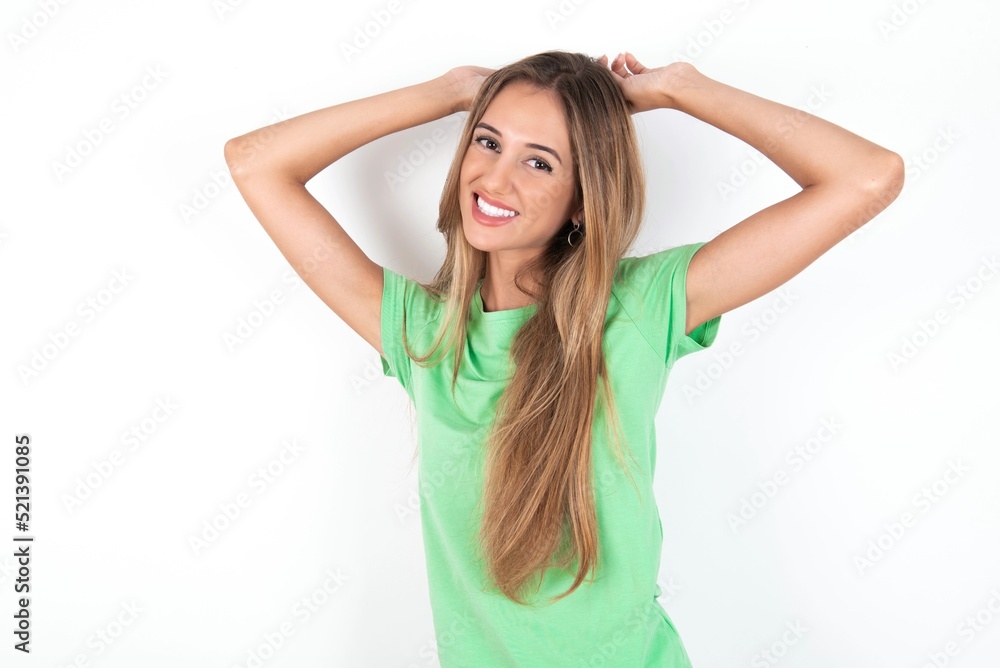 young beautiful woman wearing green T-shirt over white background stretching arms, relaxed position. young beautiful woman wearing green T-shirt over white background stretching arms, relaxed position.
