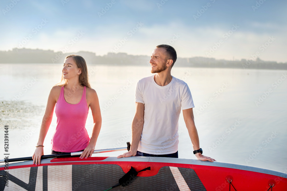 Attractive couple standing with sup board, concept of active life Attractive couple standing with sup board, concept of active life
