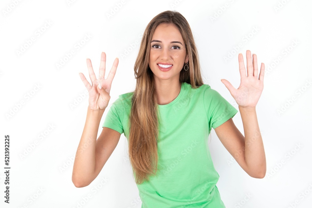 young beautiful woman wearing green T-shirt over white background showing and pointing up with fingers number nine while smiling confident and happy. young beautiful woman wearing green T-shirt over white background showing and pointing up with fingers number nine while smiling confident and happy.