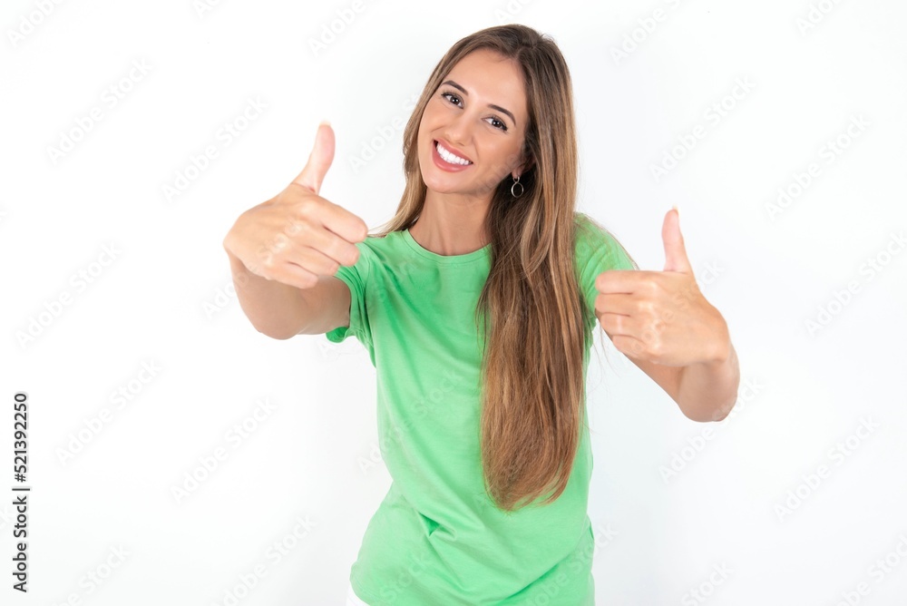 young beautiful woman wearing green T-shirt over white background, approving doing positive gesture with hand, thumbs up smiling and happy for success. Winner gesture. young beautiful woman wearing green T-shirt over white background, approving doing positive gesture with hand, thumbs up smiling and happy for success. Winner gesture.